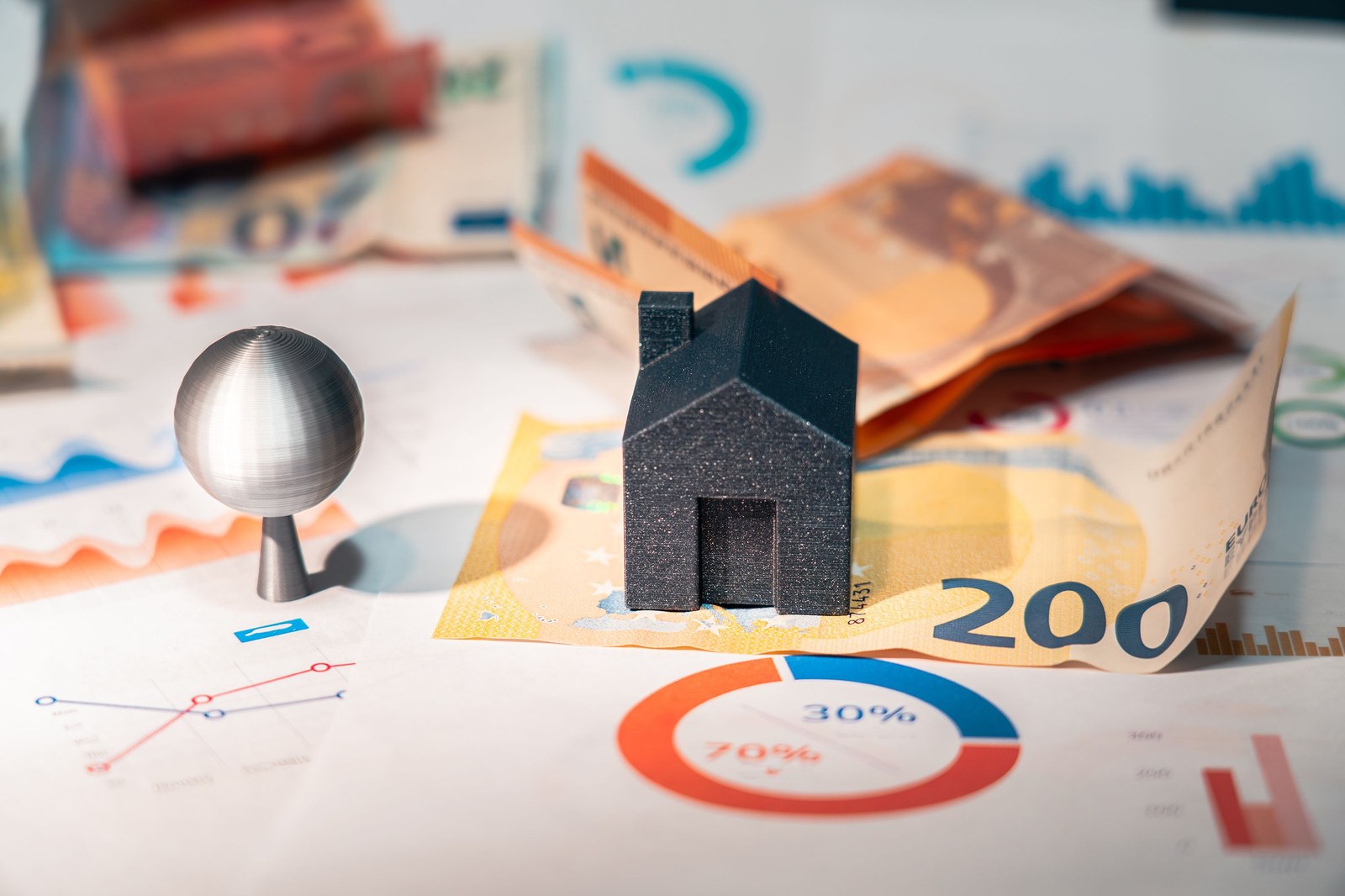 Casa en miniatura sobre billetes de euro y gráficos de precios