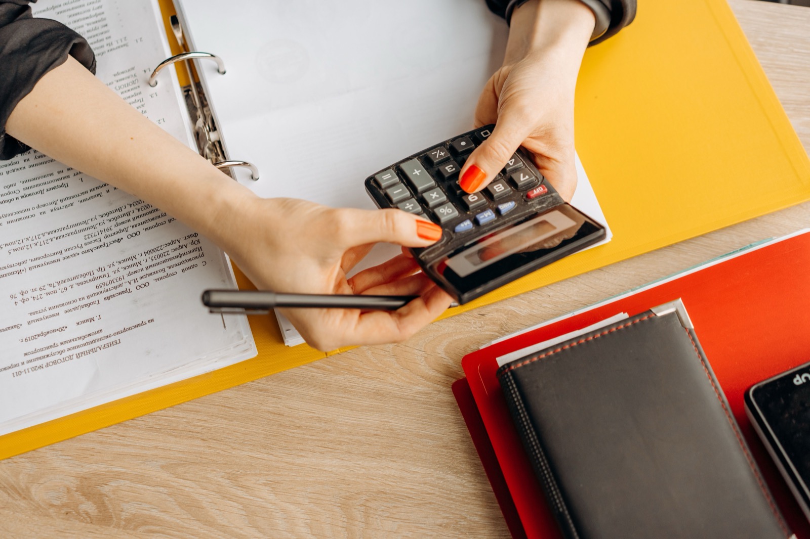 Manos usando una calculadora junto a documentos