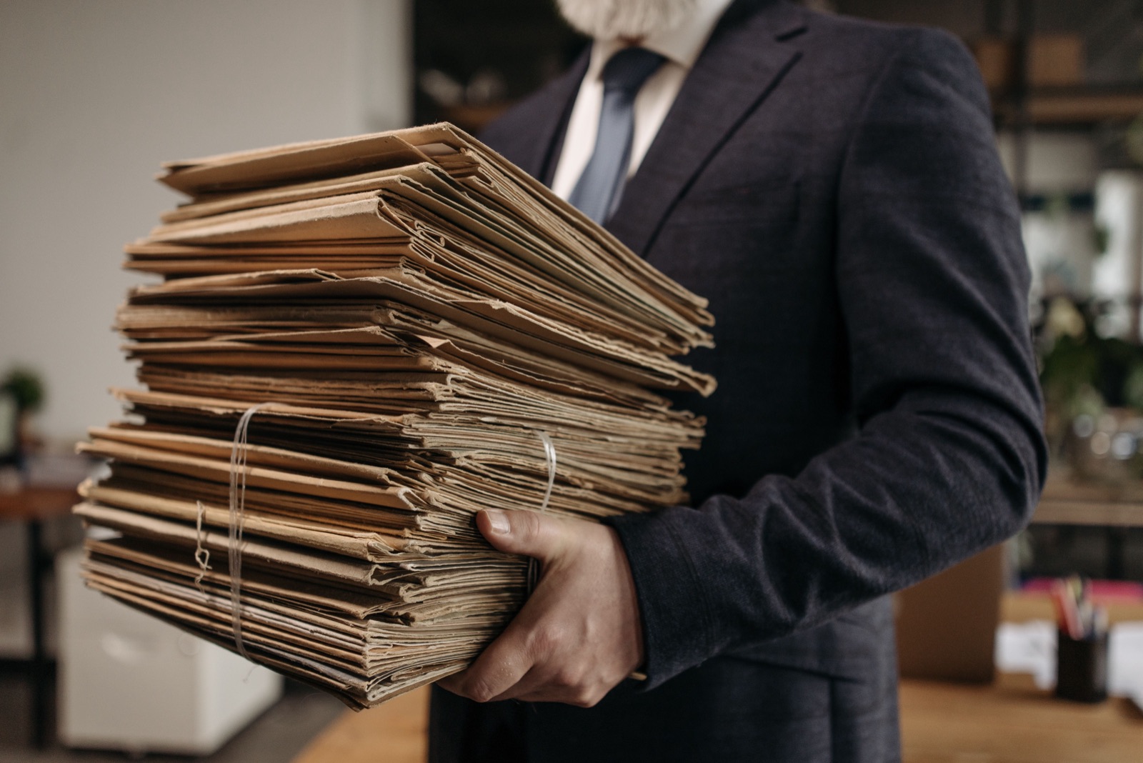 Person holding a large stack of paper folders in an office