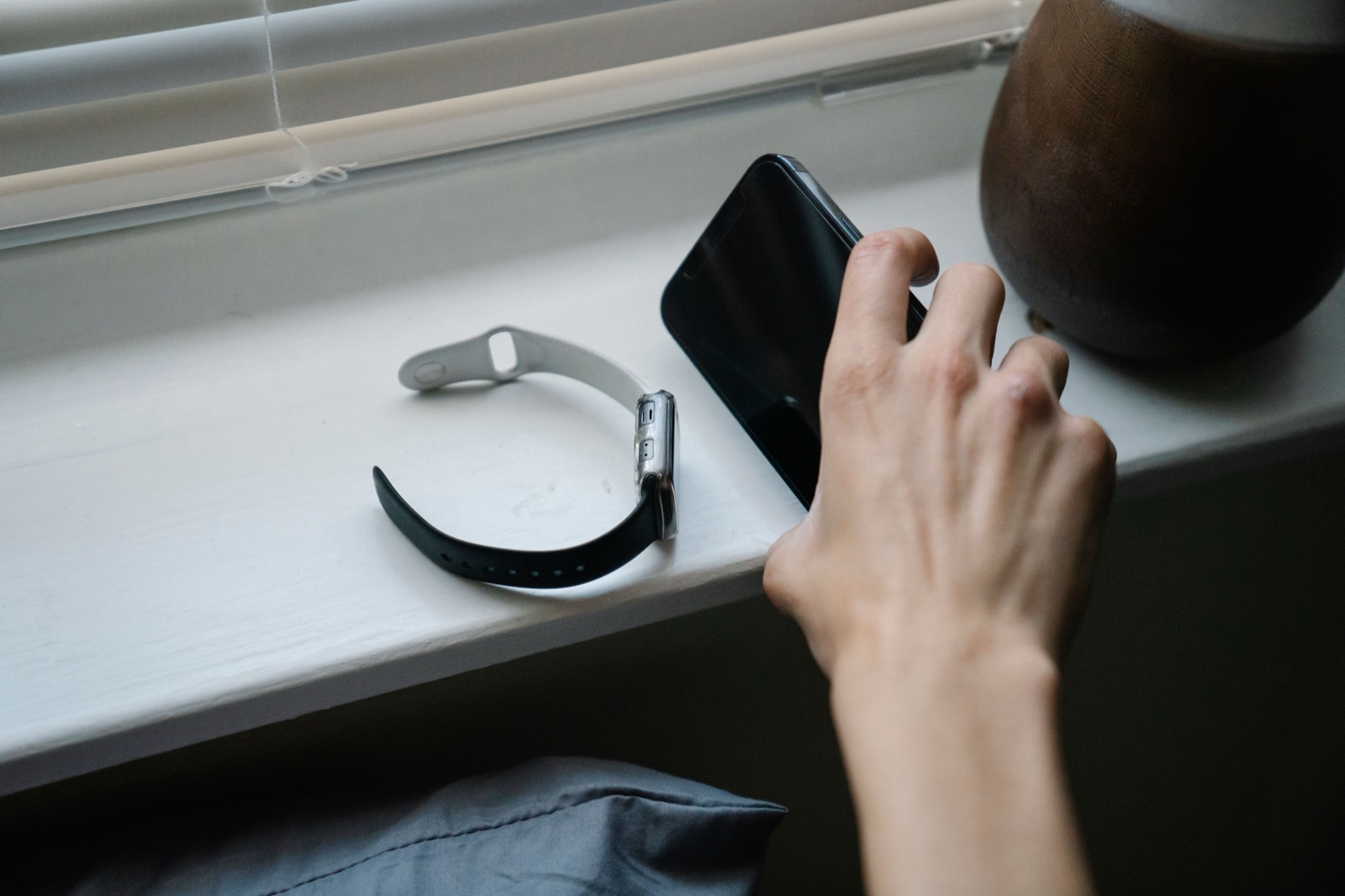 Reaching for a phone on a windowsill next to a smartwatch