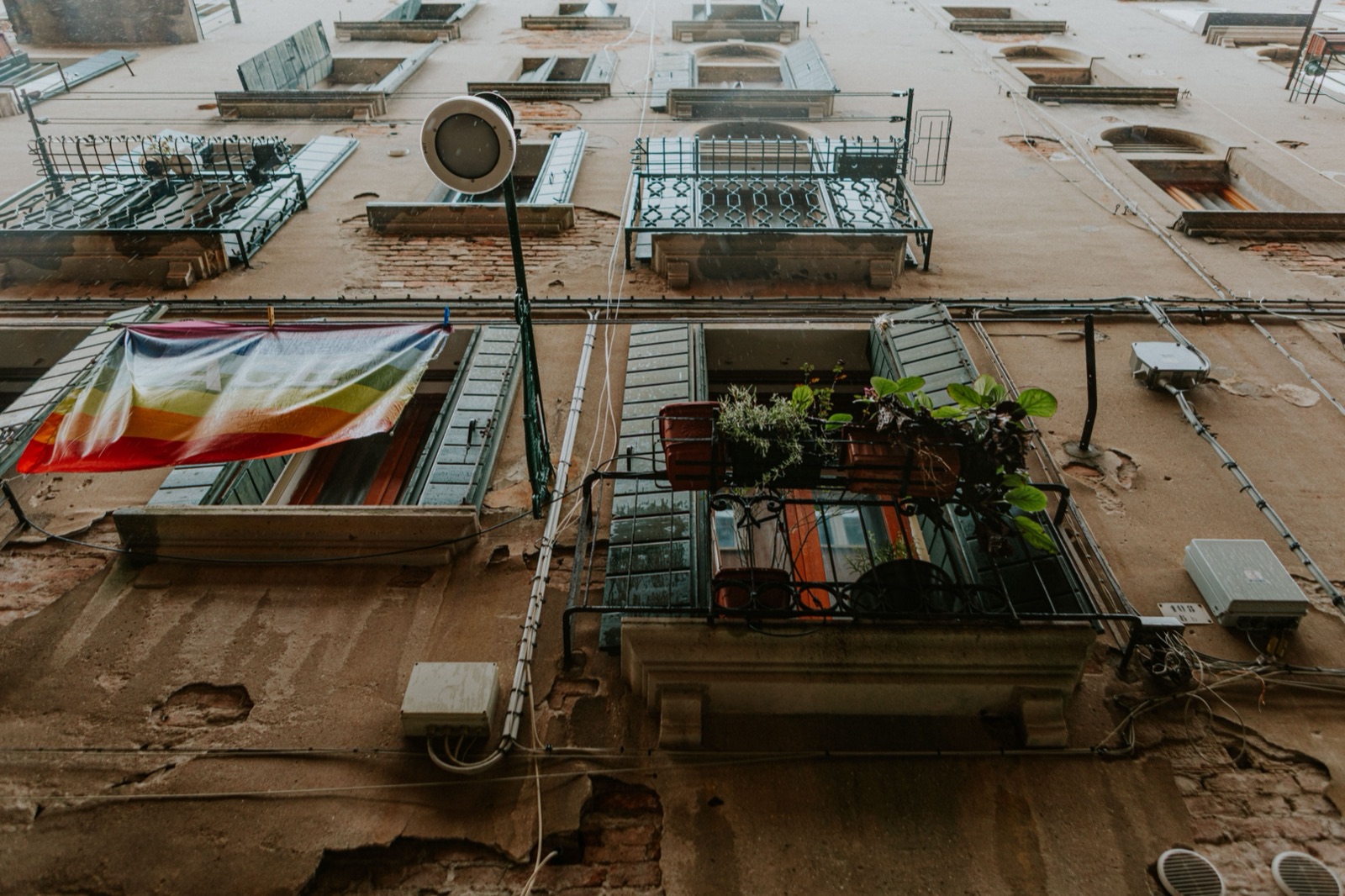 Rainbow pride flag hanging from a city apartment balcony
