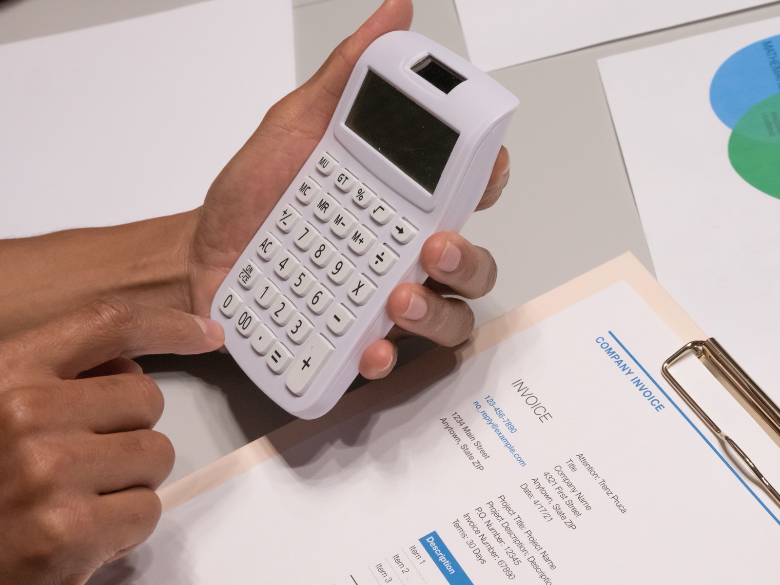 Manos usando una calculadora junto a una factura