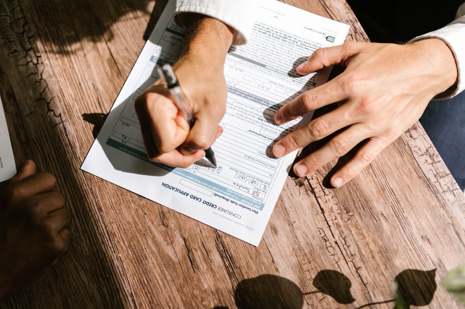 Hands filling out a bank application form