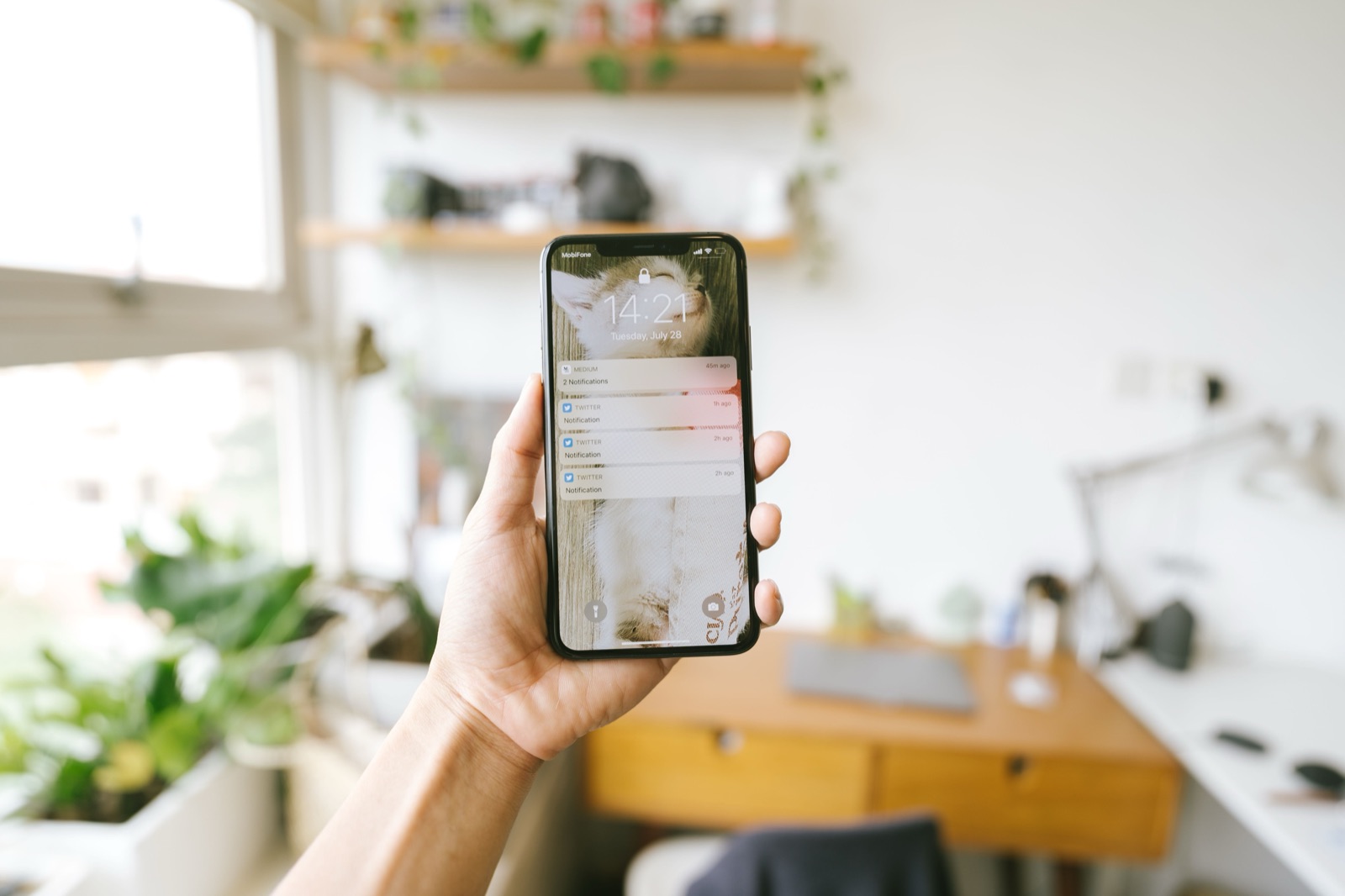 Hand holding a smartphone showing a list of unread notifications